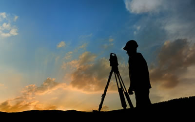 A silhouette of a land surveyor surveying a commercial real estate investment of Texas land.